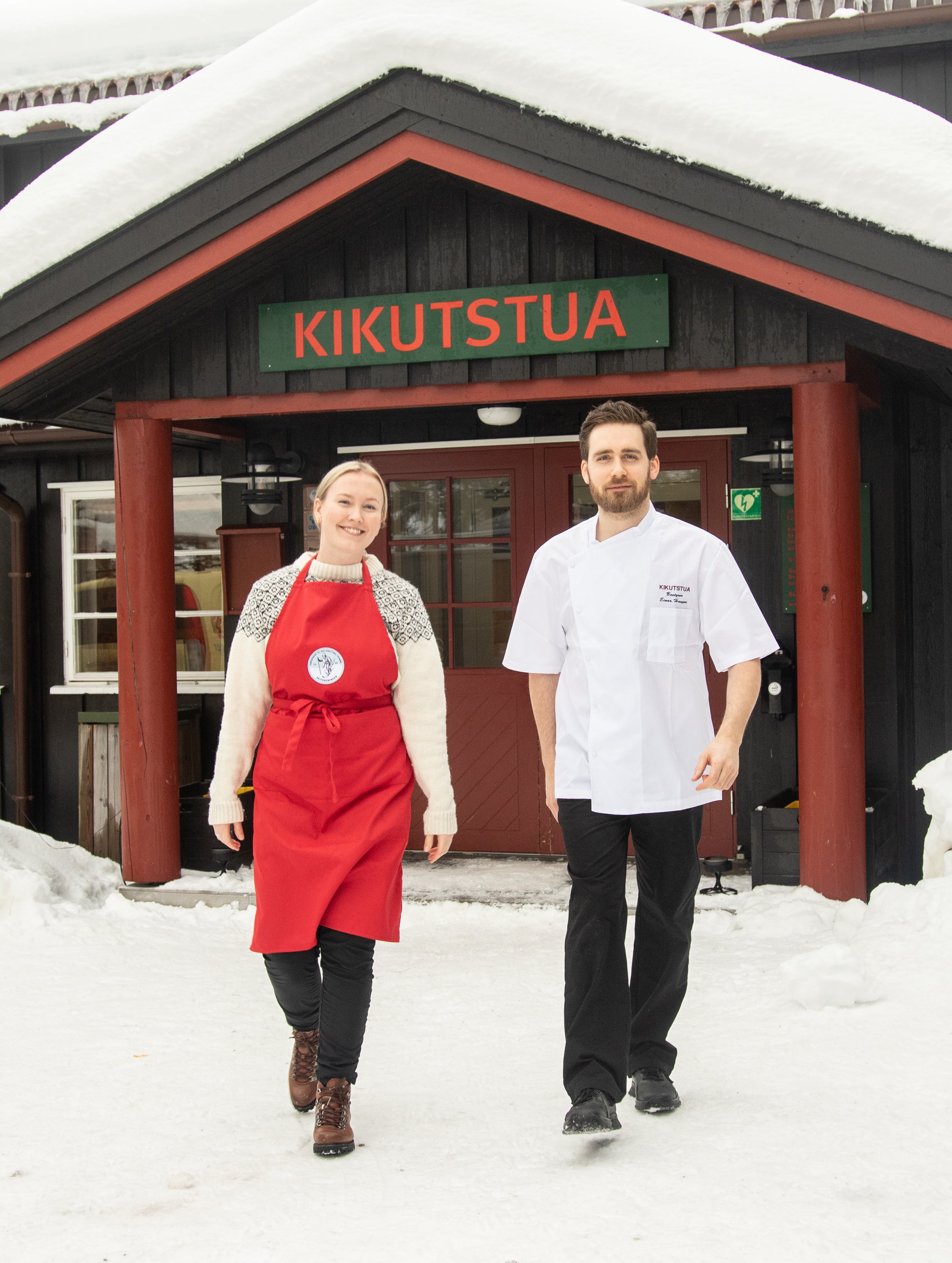Kikutstua med snø på taket og samboerparet som eier stua i Oslomarka