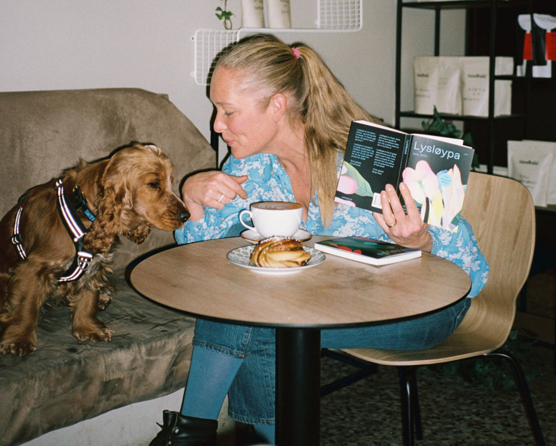 Kvinne på kafé med hund og leser Lysløypa
