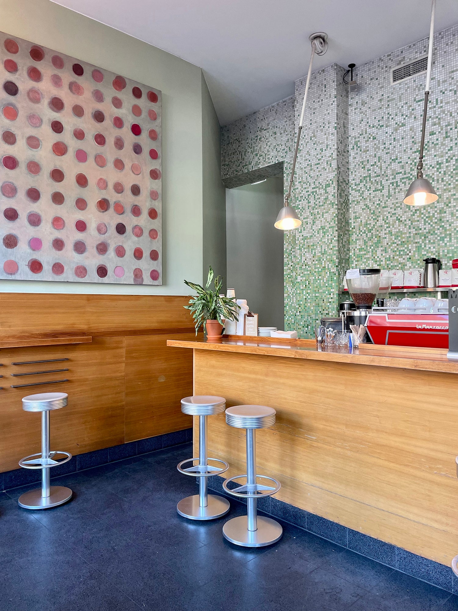 Koselig interiør med barstoler, blått gulv, kaffemaskin hos Java som driver med baristakunst i Ullevålsveien i Oslo
