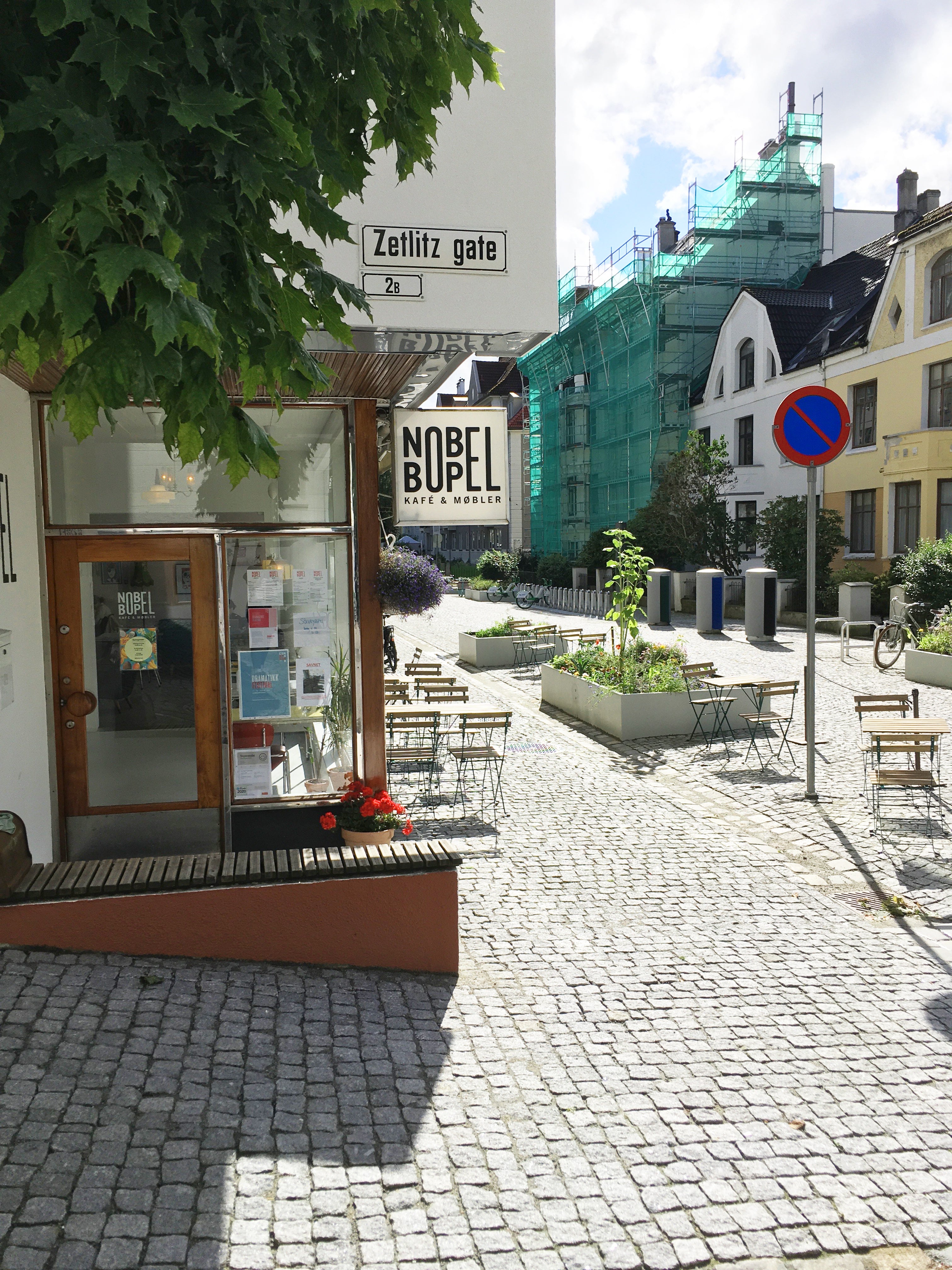 Fargerike benker og blomster med inngang til nabolagskafeen Nobel Bopel i Bergen