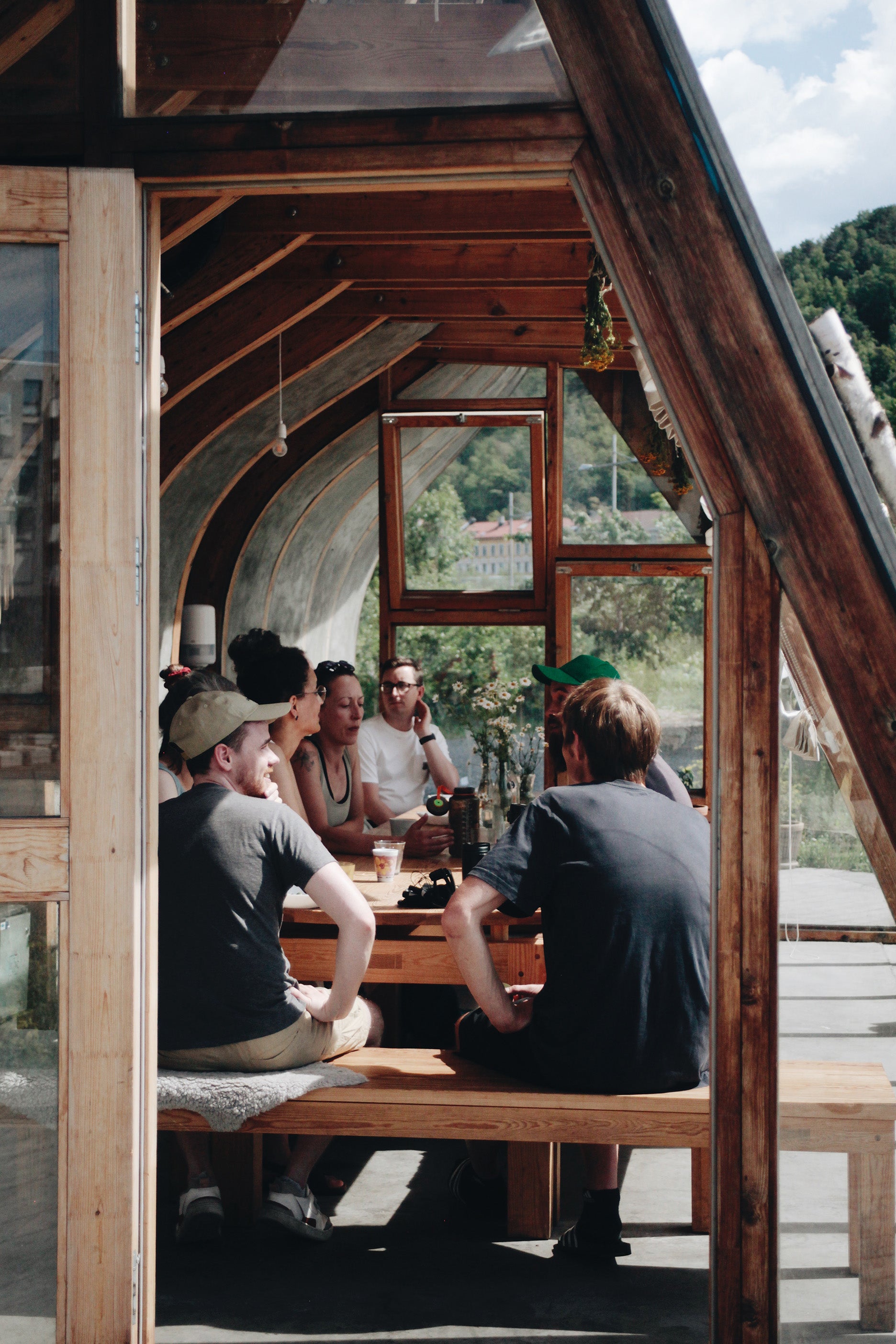 Gjester sitter rundt bord med betongvegger og trepilarer på Wilder Kitchen i Oslo